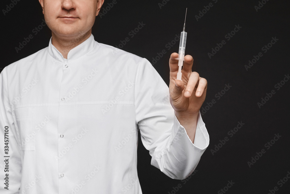 A medical syringe for injection with a vaccine in the hand of the doctor, isolated on black background with copy space. Concept of healthcare and seasonal vaccination A medical syringe for injection with a vaccine in the hand of the doctor, isolated on black background with copy space. Concept of healthcare and seasonal vaccination