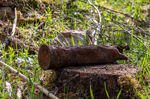 a cannon shell in a forest on a stump. Big, old rusty