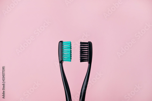 Two black toothbrushes on pink. Relationship between man and woman, Valentines Day and love concept. Backdrop with copyspace. Stock photo.
