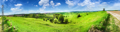 Panorama of hilly landscape with bright blue cloudy sky