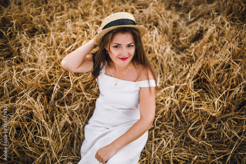 beautiful girl in a hat with brunette hair on a wheat field background. warm summer time. beautiful girl in a hat with brunette hair on a wheat field background. warm summer time.