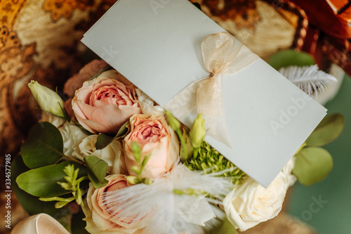 invitation card lies on a bouquet of cream roses
