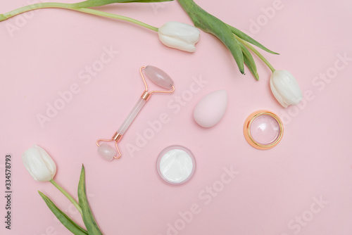 Beauty make up products on a pastel pink background with white tulips. Top view. beauty blog content  fresh blog background. 