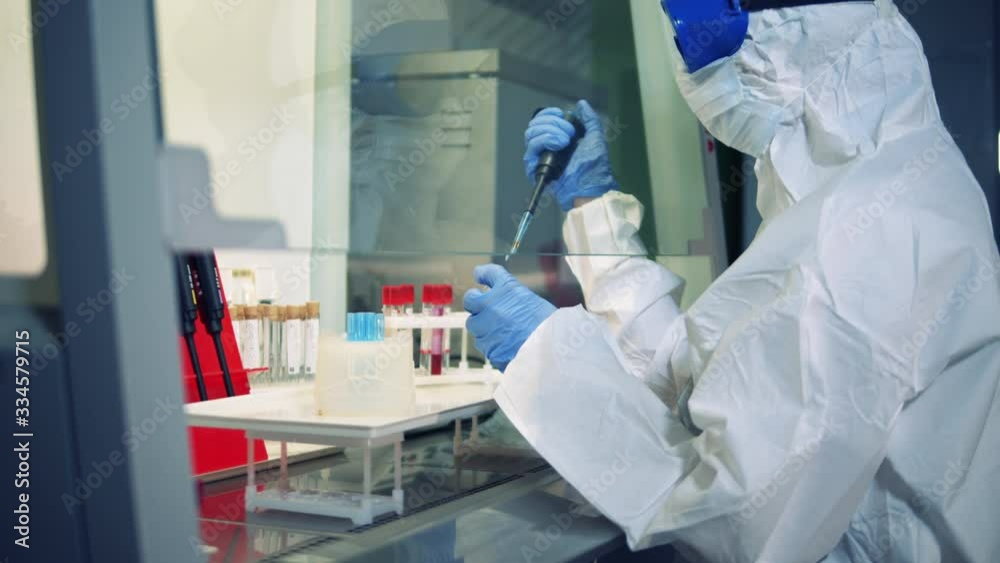 Researcher in a hazmat suit is working with chemicals Researcher in a hazmat suit is working with chemicals