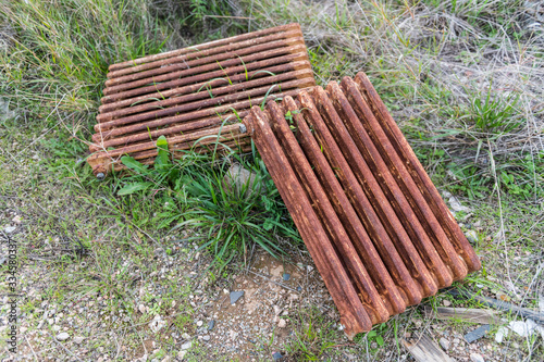 Rusty iron radiators lying on the ground on the green grass.