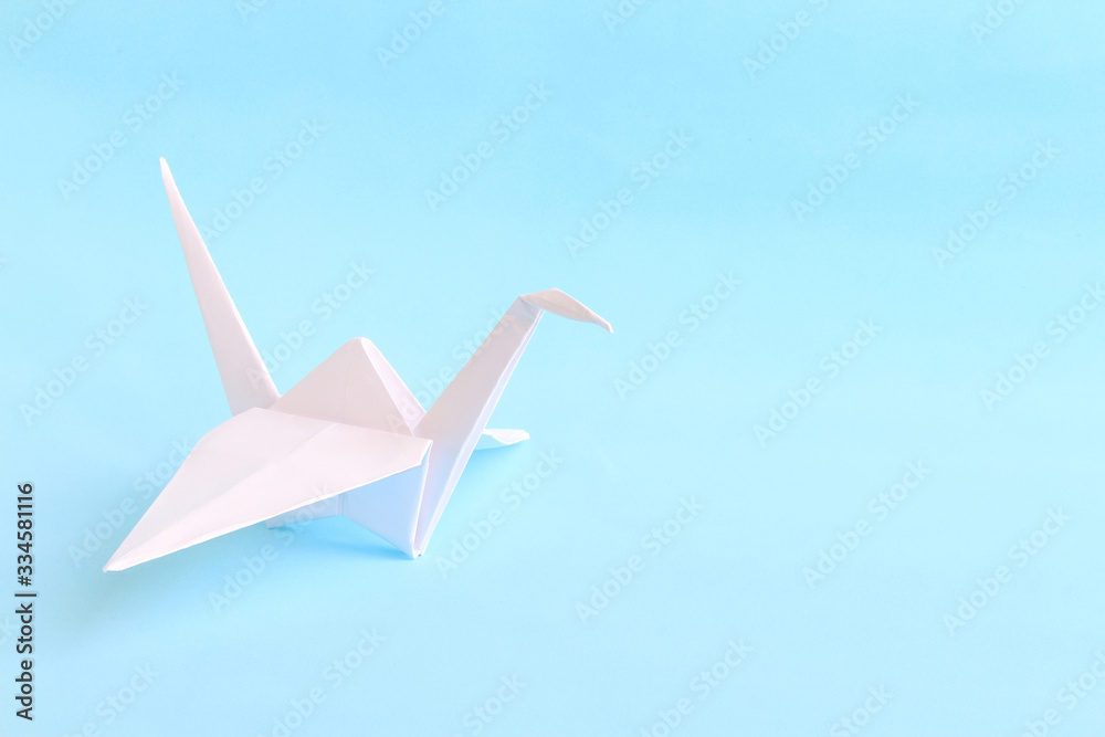 © Андрей Рыков - Handmade white origami paper crane (or orizuru) on the blue background with copy space for your text. Symbol of peace, hope and happiness. Handicrafts theme. © Андрей Рыков - Handmade white origami paper crane (or orizuru) on the blue background with copy space for your text. Symbol of peace, hope and happiness. Handicrafts theme.