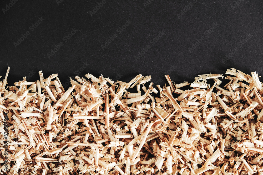 Wood shavings on black background. Background of fresh wood shavings. Copy, empty space for text