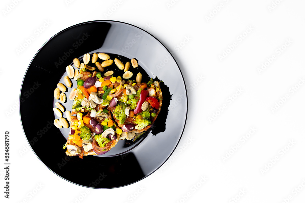Homemade vegan pizza with vegetables on black plate, white background Homemade vegan pizza with vegetables on black plate, white background