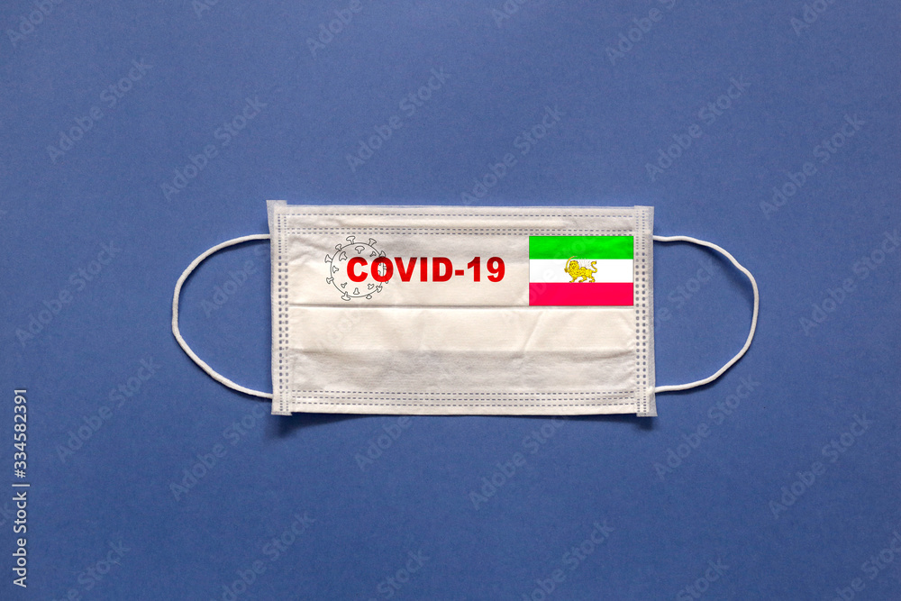 Iran flag and inscription COVID-19 on a medical mask on a blue background. Healthcare and medical concept. Pandemic virus COVID-19