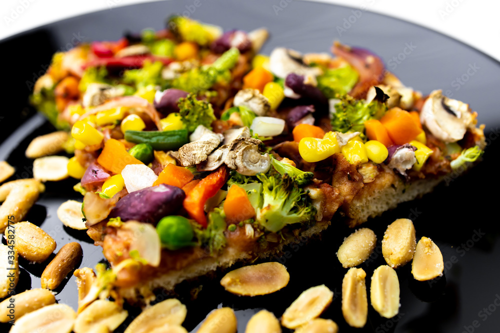 Homemade vegan pizza with vegetables on black plate, white background. Homemade vegan pizza with vegetables on black plate, white background.
