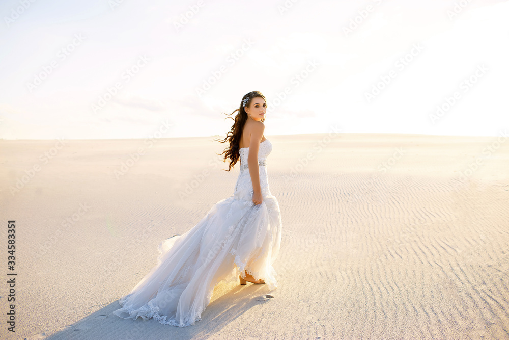 a beautiful bride in a beautiful long dress walks on the sand in the desert a beautiful bride in a beautiful long dress walks on the sand in the desert