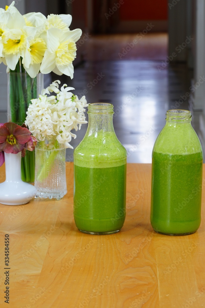 Glass bottles filled with fresh kale and ginger green smoothie Glass bottles filled with fresh kale and ginger green smoothie