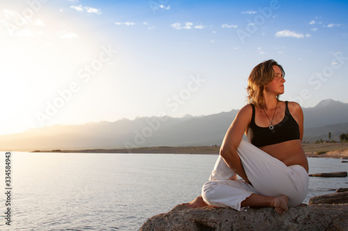 Young woman is practicing yoga in Half Lord of the Fishes Pose (Matsyendra) pose at mountain lake © Chepko Danil