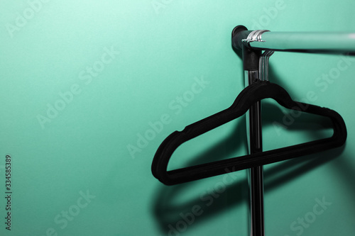 Close-up of clothes rack with black empty hangers on background of aqua menthe color.