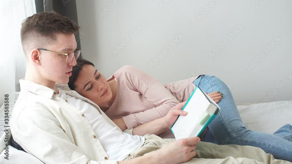 Young good looking couple enjoing reading a book in the evening, hobby, interets. Remote work in quarantine, coronavirus. Young good looking couple enjoing reading a book in the evening, hobby, interets. Remote work in quarantine, coronavirus.