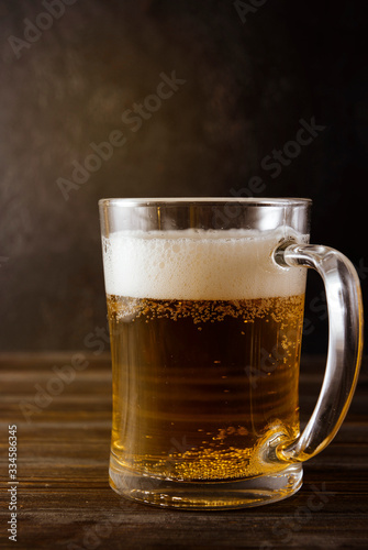 light beer, beer mug with foam on a dark wooden background, alcoholic drink