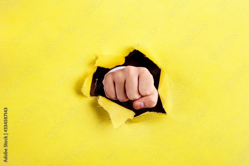Fist punching through a ripped hole in a paper - obrazy, fototapety, plakaty 