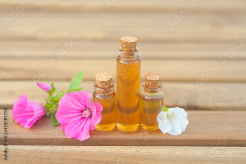 mallow essential oil in beautiful bottle on wooden background