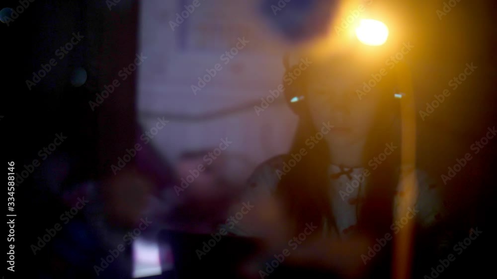 reflection in the window at night. teenager girl in pajamas and headphones watching a video on a laptop in the bedroom. reflection in the window at night. teenager girl in pajamas and headphones watching a video on a laptop in the bedroom.