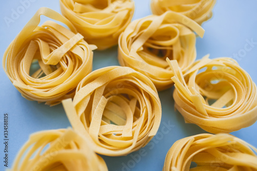 Italian wheat pasta tagliatelle isolated on blue background. Top view, close-up