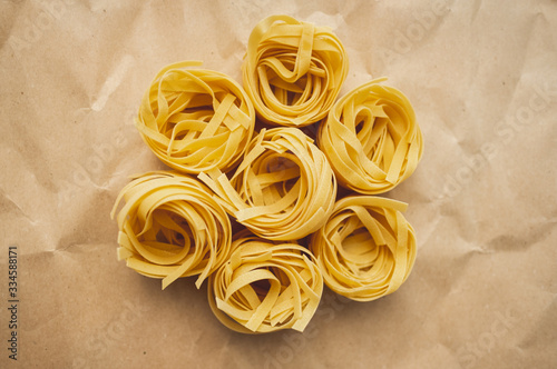 Italian wheat pasta tagliatelle on a craft paper. Top view