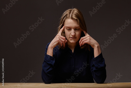 tense young woman at the table on a dark background