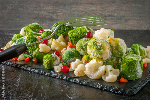Frozen vegetables and fruits on a black slate blackboard.