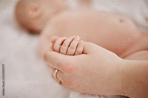 newborn holds mom by the finger