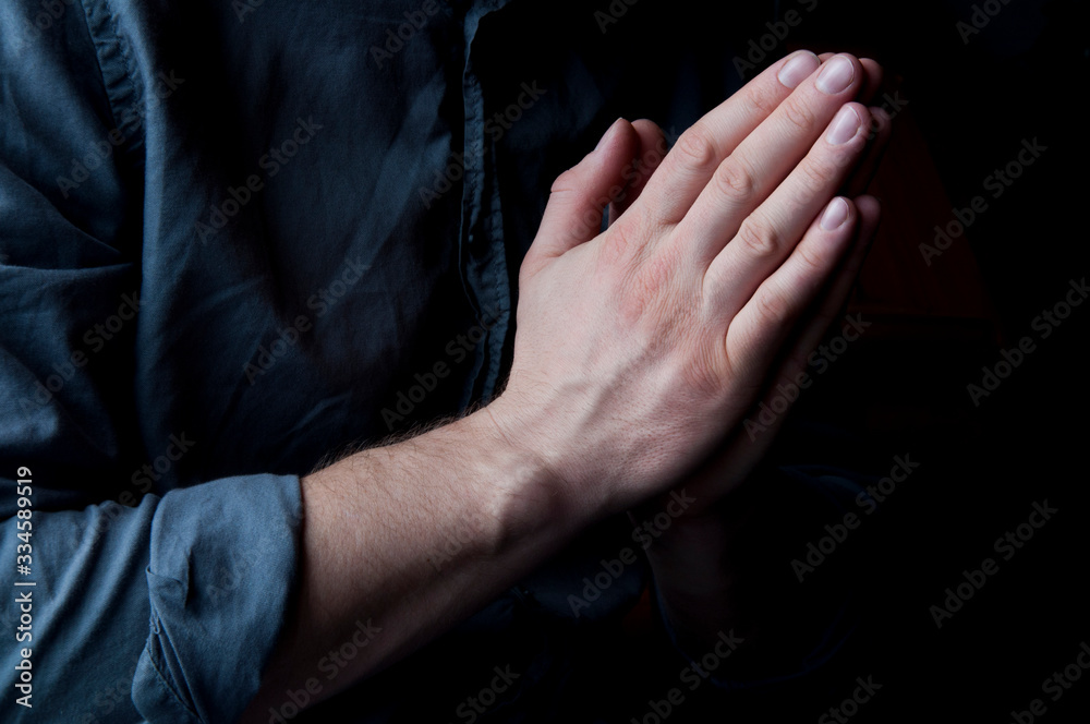 Hands in prayer. Asks God. Hands of a man in a shirt. A man is praying. Prayer position.