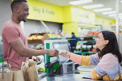 Cashier giving receipt to customer at supermarket checkout photo