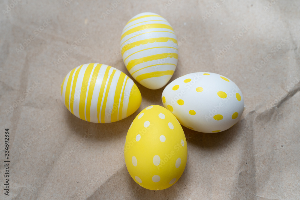 Fototapeta premium Easter yellow decorated eggs on crumpled craft paper background. Minimal easter concept. Happy Easter card with copy space for text. Top view, flatlay.