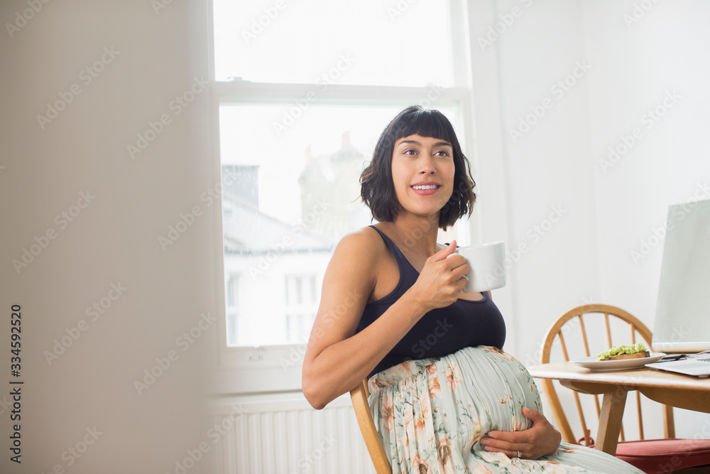 Beautiful pregnant woman drinking tea at dining table Beautiful pregnant woman drinking tea at dining table