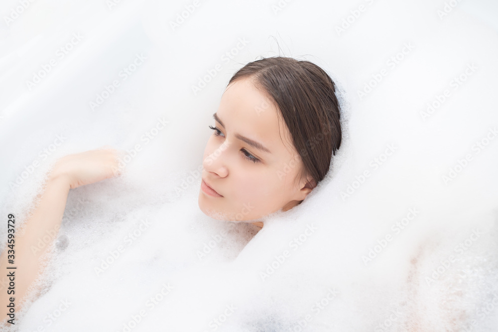 Beauty, spa, personal care. Young woman relaxes in the bath with foam Beauty, spa, personal care. Young woman relaxes in the bath with foam