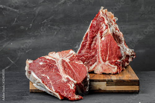 Raw T-bone steak cooking on stone table.