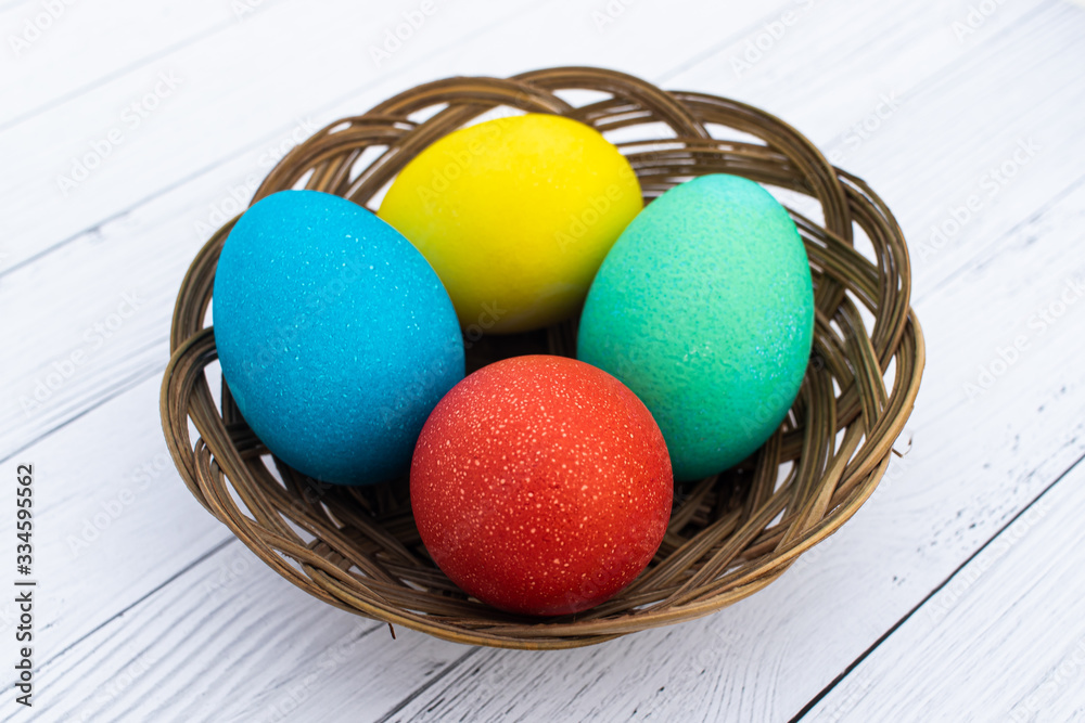 Four Easter colored plain eggs. A set of homemade eggs for Happy Easter holiday on a white wooden background. Boiled bright cooked eggs in a wicker basket Four Easter colored plain eggs. A set of homemade eggs for Happy Easter holiday on a white wooden background. Boiled bright cooked eggs in a wicker basket