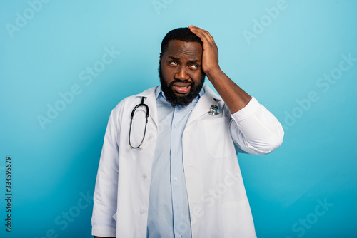 Scared doctor face expression due to coronavirus pandemic. Blue background © alphaspirit