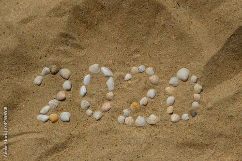 Figure 2020 laid out from seashells on the sea sand. The concept of the new year.