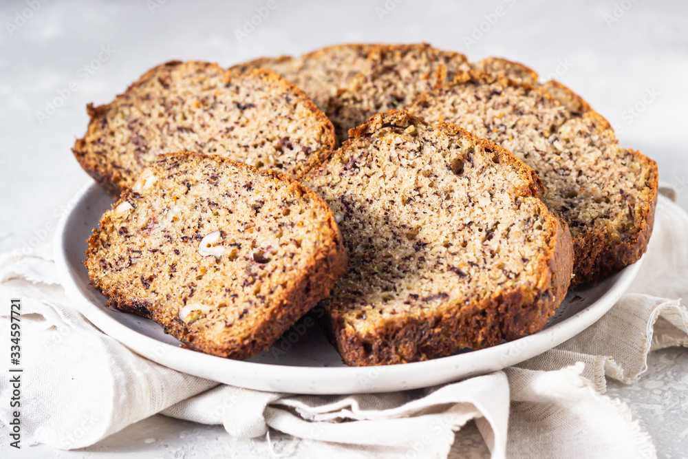 Sliced hazelnuts and banana loaf cake on a ceramic plate. Selective focus, top view. Sliced hazelnuts and banana loaf cake on a ceramic plate. Selective focus, top view.