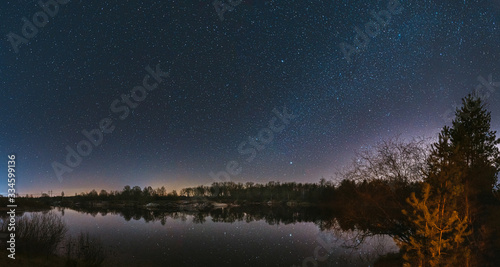 Belarus, Eastern Europe. Night Sky Stars Above Countryside Landscape With River. Natural Starry Sky Above Lake Pond In Early Spring Night. Russian Nature