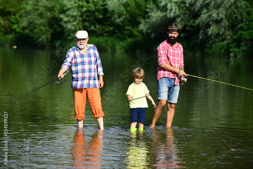 Grandfather, father and grandson fishing together. Coming together. Fly fishing. Father teaching his son fishing against view of river and landscape.