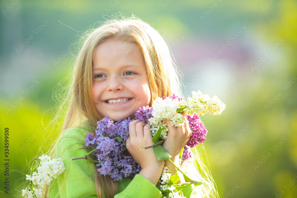 Fototapeta premium Young spring girl in spring garden. Young lady feeling happy in nature. Facial portrait of funny teenager girl. Girl with bouquet of lilac.