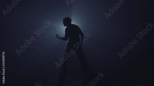 A burglar with crowbar in dark