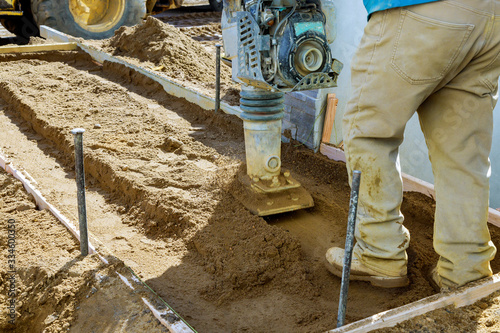 Compaction sand ground with vibration plate compactor machine on sidewalk photo