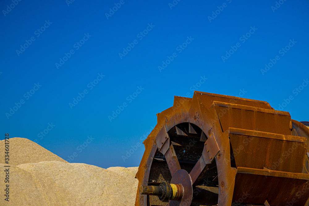 Rusty machine and gravel extraction versus blue sky