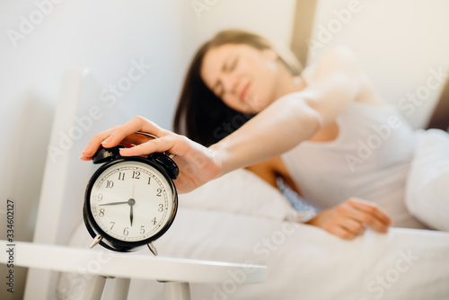 Alarm clock ringing.Woman waking up in early morning for work.Sleeping disorder.Tired woman oversleeping,bad sleep quality.Sleep deprived mom.Waking inertia,bad mood after dreaming nightmares.Insomnia photo