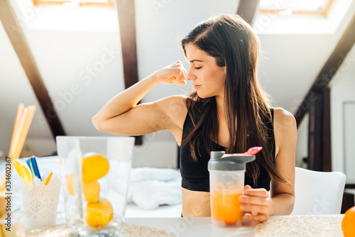 Woman at home drinking orange flavored amino acid vitamin powder.Keto supplement.After exercise liquid meal.Weight loss fitness nutrition diet.Immune system support.Organic citrus fruit.Strong body