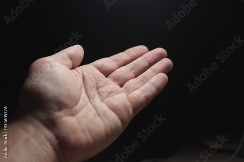 Close-up of a man's hand on a black background.