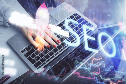 Double exposure of woman hands working on computer and seo hologram drawing. internet search concept.