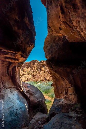 A vertical landscape from the inside of a subway-shaped second story slot canyon through red sandstone in Gold Butte National Monument