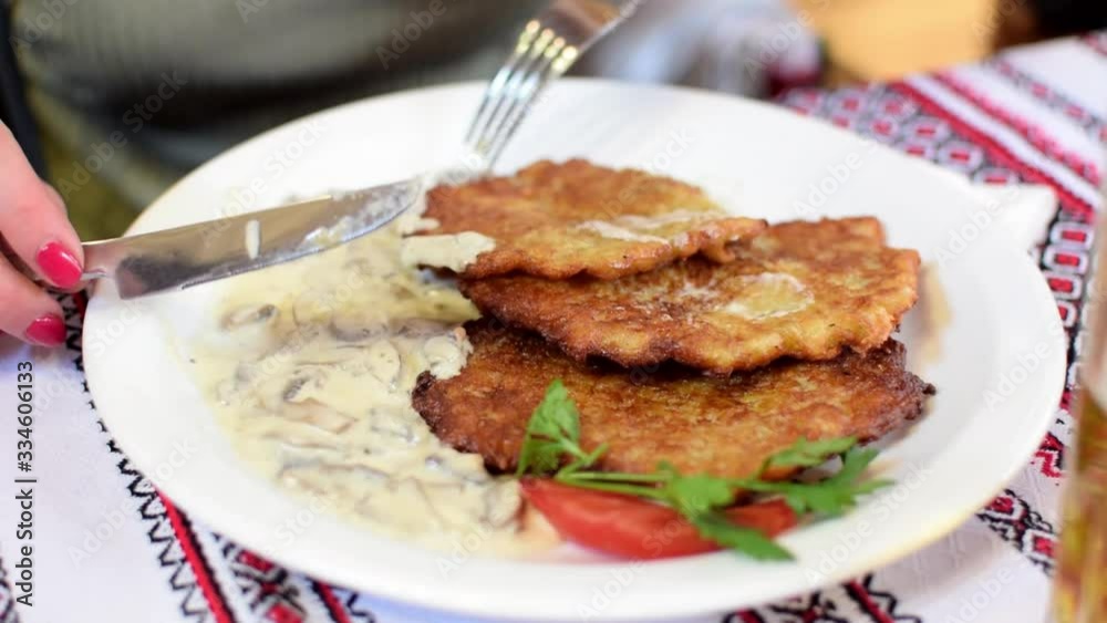 Eat potato pancakes from a plate. A fork breaks them into pieces. Eat potato pancakes from a plate. A fork breaks them into pieces.
